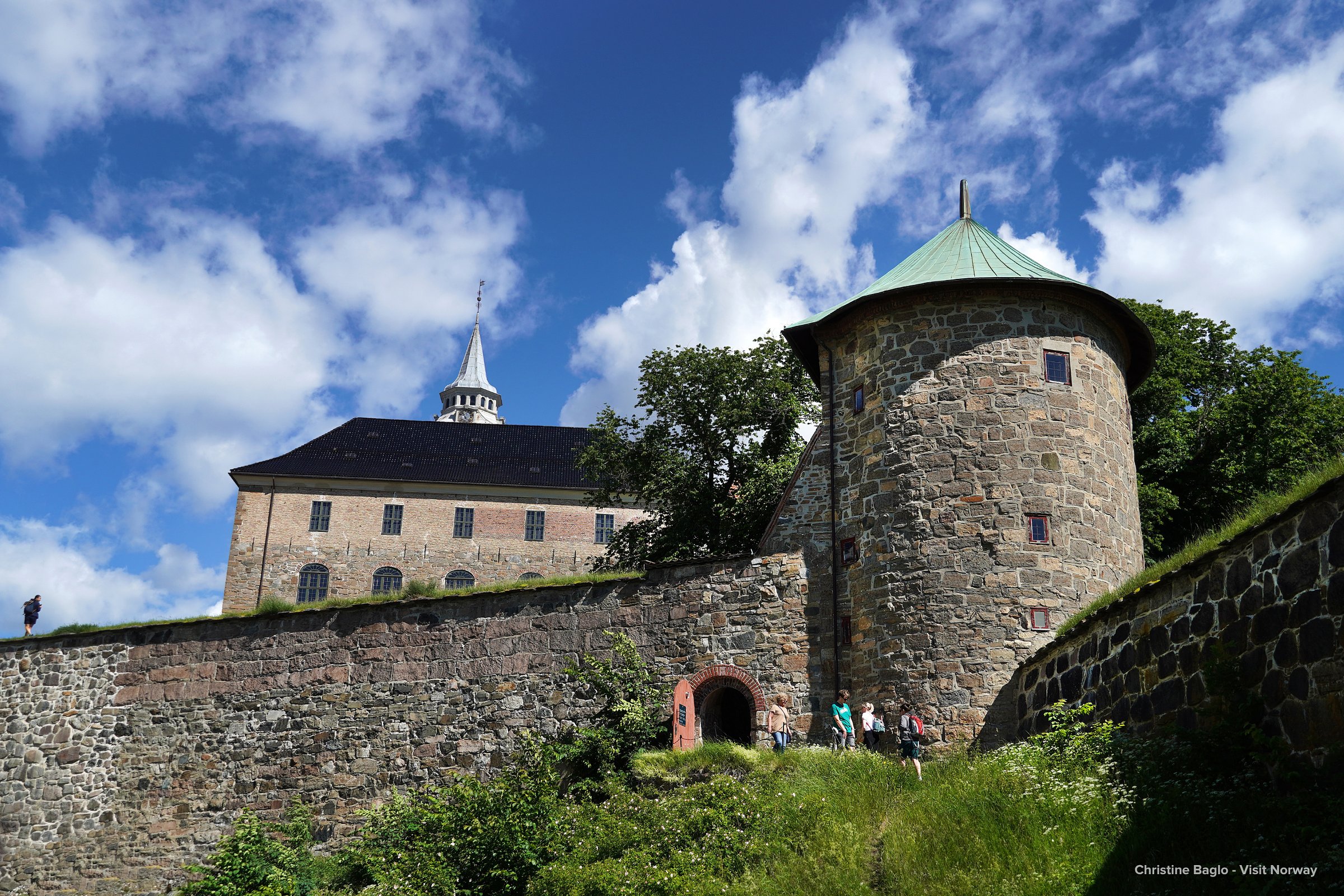 Stone walls and towers of medieval Akershus Fortress in Oslo against a blue sky with scattered clouds